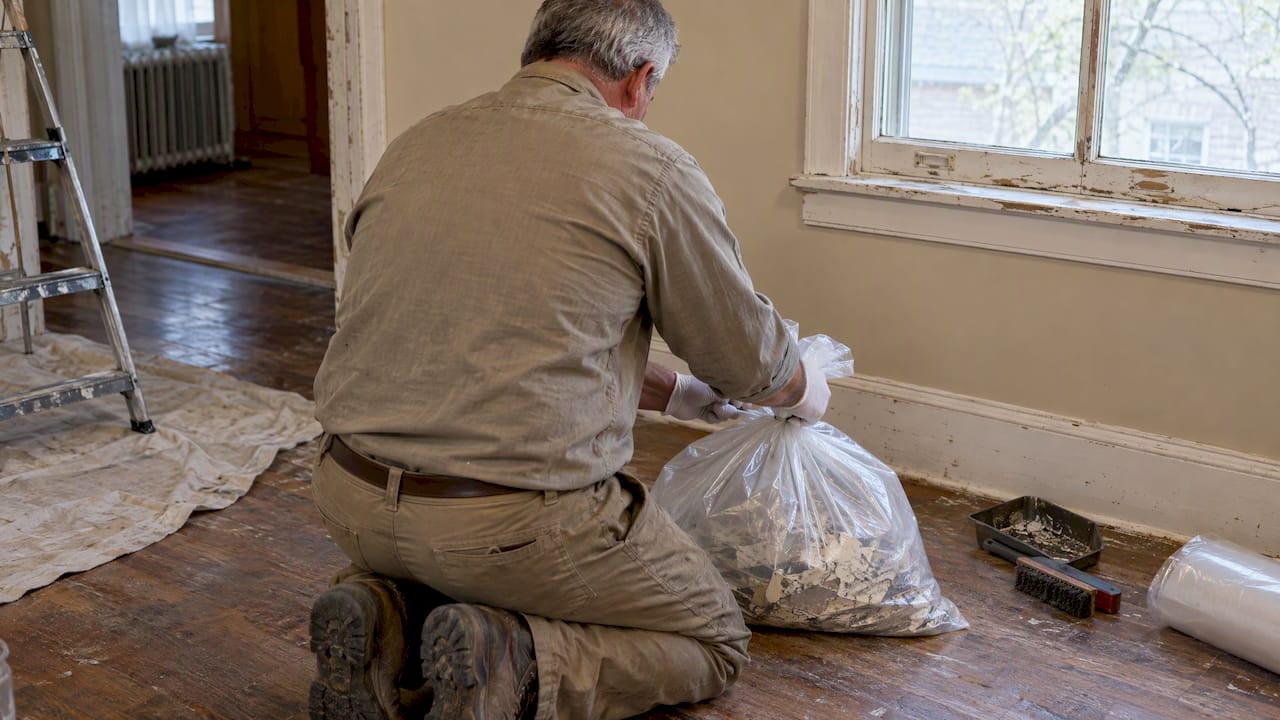 Homeowner sealing lead paint debris in plastic