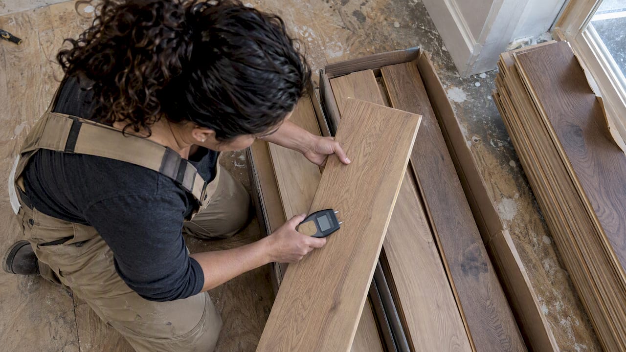 Installer sampling flooring boards with moisture meter